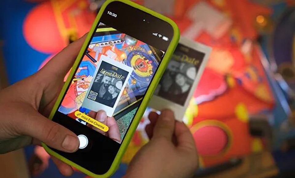 A smartphone scanning the QR code on an instax print to play the associated video